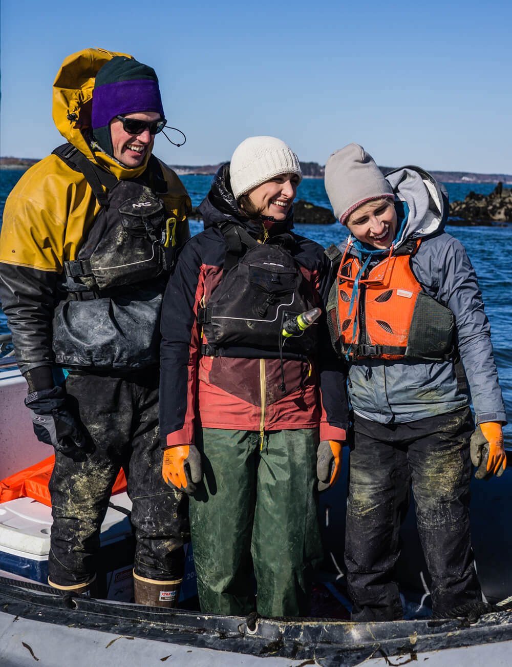 photo of james crimp, briana warner, and melissa dipalma in cold weather attire and wading boots standing in a boat
